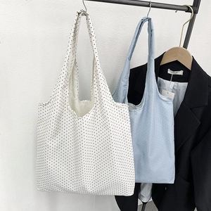 Close-up of polka dot canvas tote bags hanging on a rack with a dark blazer