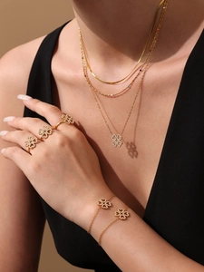 Dettaglio di parure a quadrifoglio con collana e anello indossati su modella