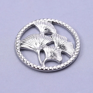 Detailed view of silver stainless steel ginkgo leaf pendant with beaded circular border