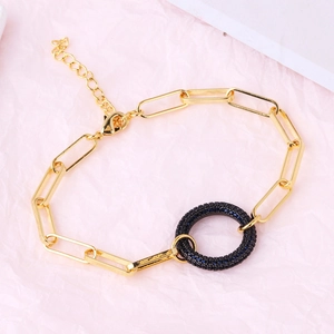 Detail of gold-plated paperclip chain bracelet with a black micro-pave encrusted charm