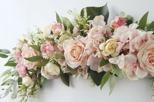 Detail of pink and champagne artificial rose flower row with lush green leaves