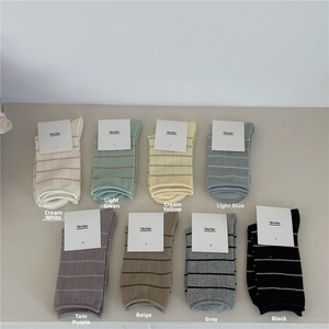 Flat lay of 8-color Morandi stripe crew socks with curled edges and brand tags
