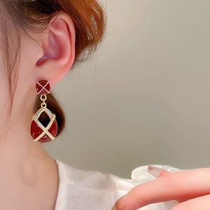 Vue détaillée de boucles d'oreilles vintage en émail rouge foncé avec motifs croisés dorés