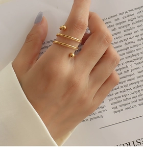 Close-up of golden spiral twisted ring with beads on a magazine background