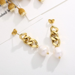 Détail des boucles d'oreilles chaîne dorée avec perles blanches sur un fond blanc élégant