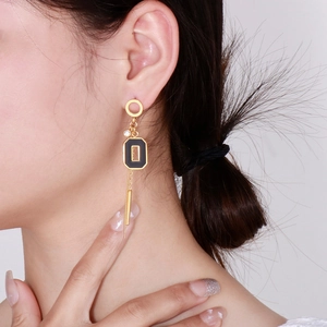 Détail de boucles d'oreilles à pompons avec pendentif noir et accents dorés