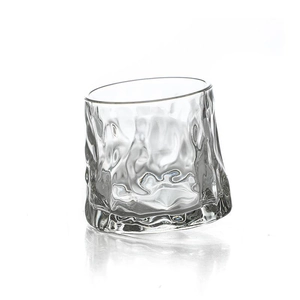 Rotating glass whiskey tumbler with creative rock texture on a white background