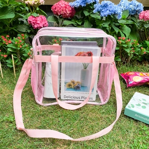 Detailansicht der klaren PVC-Reisetasche mit rosa Henkeln vor blumigem Hintergrund