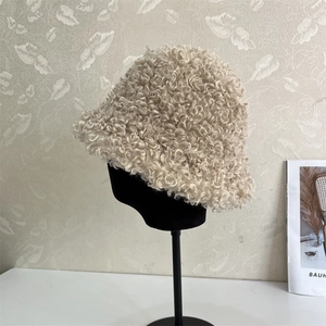 Close-up of curly plush texture and thick lambswool material on beige bucket hat