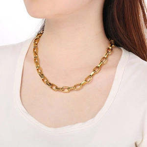 Close-up of a chunky golden Cuban link necklace worn by a model against a white background
