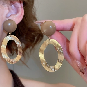 Detailed close-up of brushed gold oval drop earrings with elegant brown resin beads