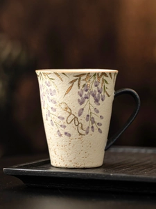 Macro shot of hand-painted wisteria and gold details on ceramic mug with handle