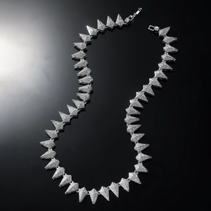 Macro detail of iced-out silver geometric triangle necklace with shimmering crystals