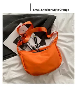Detail of orange nylon half-moon crossbody bag with sneaker charm and daisy strap decor