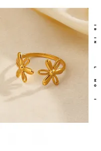 Detail view of a gold flower open ring with two floral motifs on a textured fabric