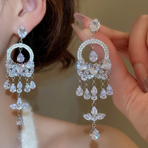 Detail of silver drop earrings featuring heart, circle, and teardrop zircon tassels