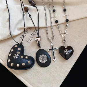 Gothic leather heart and silver cross pendant necklaces set on beige canvas background