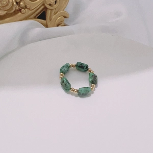 Detailed close-up of handmade elastic ring with green ink stones and gold beads