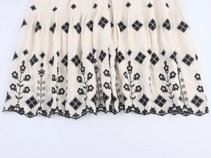 Detailed view of the bohemian embroidered hem on a cream cotton linen maxi dress