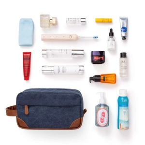 Detail view of the canvas toiletry bag organized with grooming accessories on white background.
