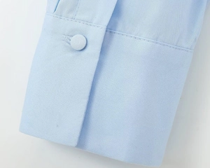 Detail of light blue poplin shirt sleeve featuring a matching fabric-covered button