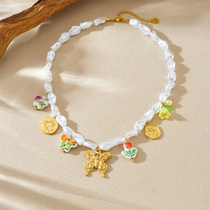 Baroque pearl necklace with gold butterfly, ceramic flower and insect charms on wood background