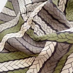 Close-up of woven rope pattern on soft green and grey fashion silk scarf fabric