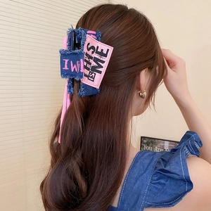 Detail showing the denim and pink bow claw clip used in a half-up hairstyle