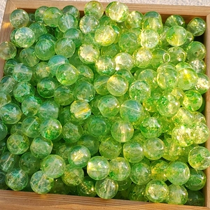Macro shot of grass green cracked glass beads for DIY jewelry making on wooden tray