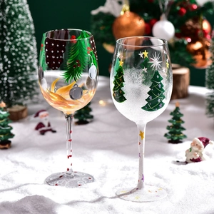 Hand-painted Christmas tree and snowman wine glasses on snow with festive decor