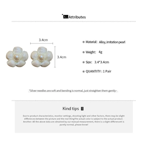 Close-up of white fabric flower earrings with faux pearls and silver needles detail