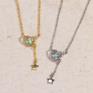 Gold and silver heart planet pendant necklaces with opal luster on beige linen fabric
