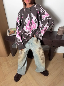 Detailed close-up of dark grey ikat knit sweater with loose-fit vintage light blue jeans