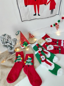 Détail de chaussettes de Noël en polaire corail avec pompons et motifs festifs