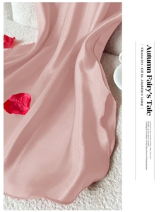 Gros plan du tissu satiné rose mat de la chemise de nuit avec couture fine sur tapis