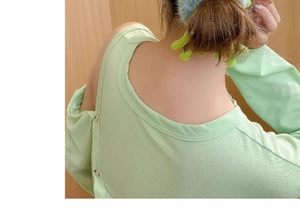 Close-up of a green plush frog hair scrunchie on a ponytail with cutout shoulder detail