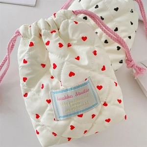 Detail of cream quilted camera pouch with red heart patterns and pink drawstring cord