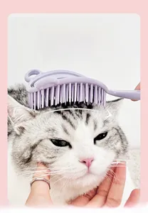 Dettaglio della spazzola massaggiante viola curva per animali sulla testa di un gatto