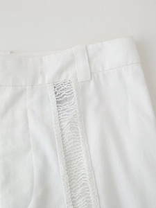 Détail de pantalon blanc avec dentelle ajourée verticale et tissu en coton mélangé