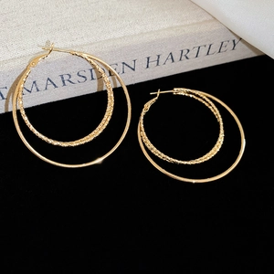 Detail of 18k gold plated double hoop earrings with twisted and smooth metal textures
