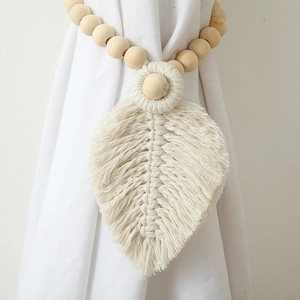 Detail of bohemian curtain tieback with natural wooden beads and macrame leaf pendant