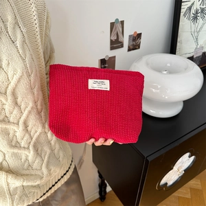 Close-up of model holding red corduroy cosmetic bag with woven patch detail