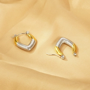 Close-up of geometric U-shaped earrings with dual-tone metal and textured stripes