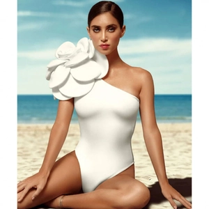 White one-shoulder swimsuit featuring a large 3D floral decoration on beach background