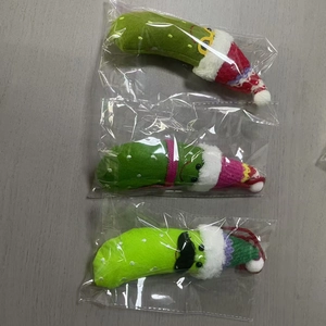Three handmade crochet pickled cucumbers with hats and accessories in packaging