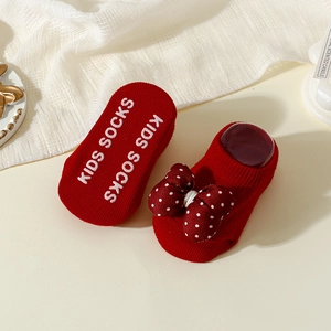 Close-up of red polka dot bow baby socks with non-slip silicone grips on the soles