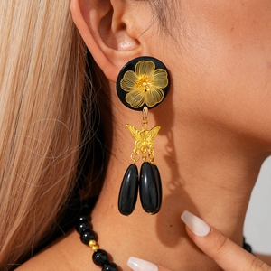 Macro view of vintage black beaded necklace with gold flower pendant and butterfly details