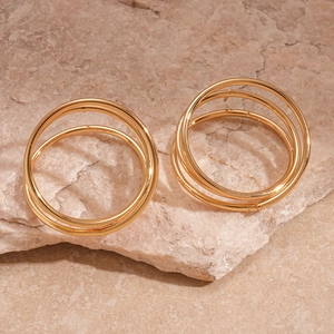 Detail view of gold multi-layered circular twist earrings on a natural stone base