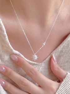 Detail of S925 silver sunburst necklace with star accent on model wearing knit sweater