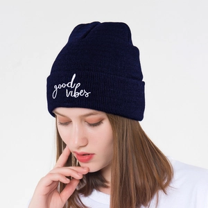 Detail of navy knit beanie featuring white 'good vibes' script embroidery on the cuff